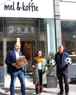 Peter Ostendorf von mel&koffie, Sya Ahmad, Bezirksvorsteherin neunter Bezirk und Georg Jelenko, Leiter Samariterbund Sozialmärkte vor mel&koffie Filiale im neunten Bezirk, halten Fußbälle, Springseile und einen Leib Brot in der Hand