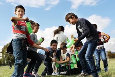 Kinder am Fußballplatz trinken Wasser aus Trinkflaschen