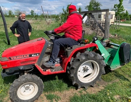 roter Traktor fährt über eine Wiese