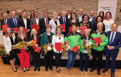 Gruppenfoto von Personen, die mit Urkunden und Blumen ausgezeichnet wurden.