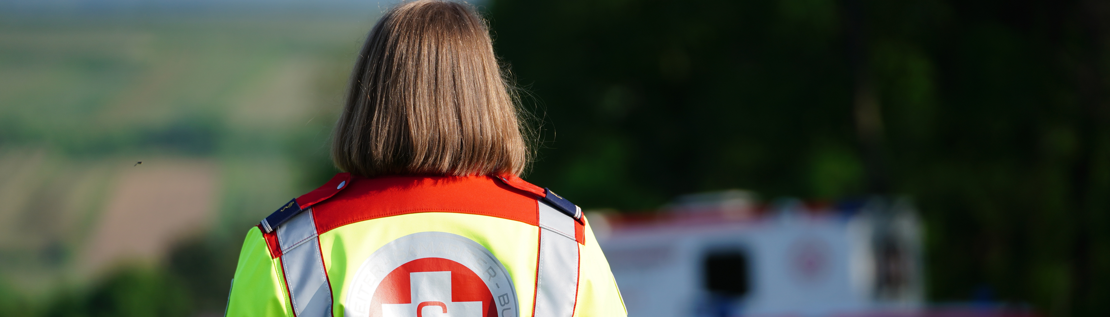 Samariterin in Uniform, KTW im Hintergrund