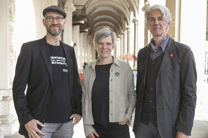 Gruppenfoto mit zwei Männern und einer Frau in der Mitte