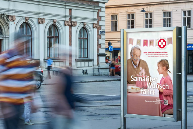 Citylight mit Wunschfahrt-Plakat im städtischen Umfeld