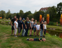 Mehrere Kinder und Betreuerinnen stehen nebeneinander auf einer Wiese. 