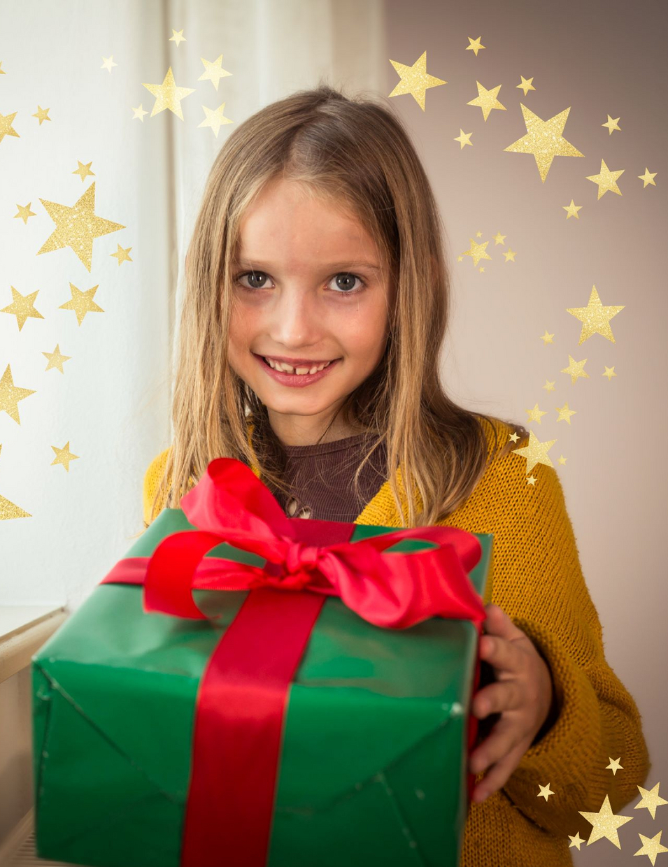 Kind hält Weihnachtsgeschenk in Händen und freut sich