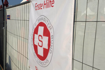 Aufschrift Erste Hilfe und Samariter Logo auf Bauzaun