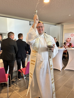 Der Priester/bischoff am Weihwasser verstreuen