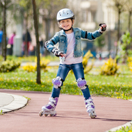 Kind fährt Rollschuhe und trägt Protektoren