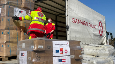 Hilfsgüter in Paletten werden aus LKW ausgeladen und gestapelt