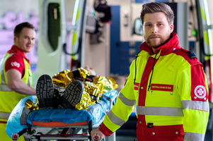 Sanitäter mit Verletztem auf Trage vor Rettungsauto