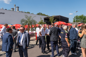 Gruppenaufnahme mehrere Personen rund um neue Zentrale und Bühne bei Eröffnungsfeier