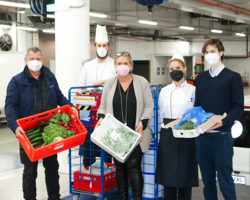 Gruppenfoto 5 Personen, alle tragen FPP2-Maske, sind in einer Lagerhalle und halten Kisten mit Lebensmittelspenden ins Foto