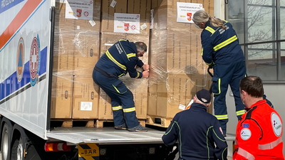 Vier Männer laden Paletten aus einem LKW aus.