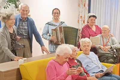 Ehrenamtliche Helferin musiziert mit Seniorinnen.