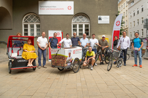 Gruppe von menschen mit Rikscha und Elektro-Auslieferungsfahrrad für Essen auf Rädern